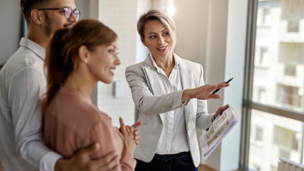 Un agente immobiliare sorridente che parla con una coppia interessata all'acquisto