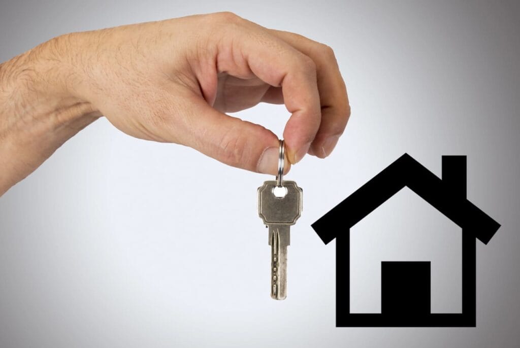 mano che tende una chiave verso una casa