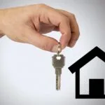 mano che tende una chiave verso una casa