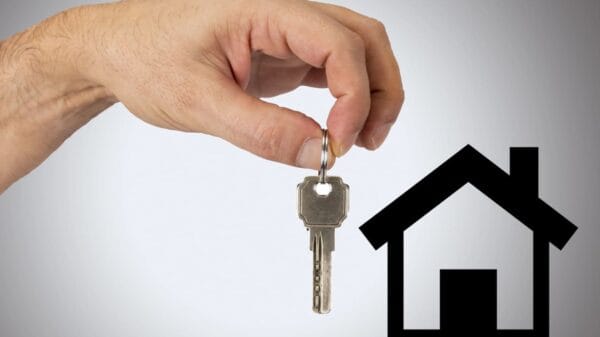 mano che tende una chiave verso una casa