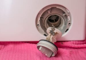 Primo piano della pulizia del filtro della lavatrice, con lo sporco chiaramente visibile