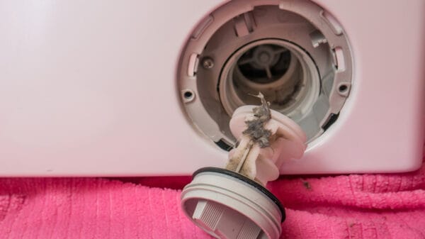 Primo piano della pulizia del filtro della lavatrice, con lo sporco chiaramente visibile