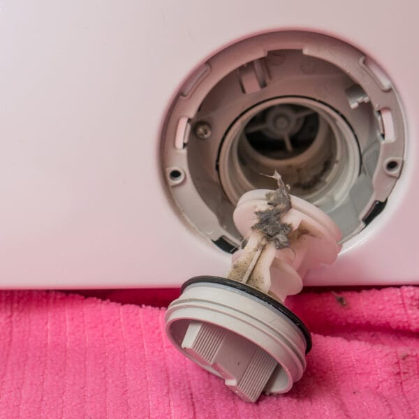 Primo piano della pulizia del filtro della lavatrice, con lo sporco chiaramente visibile