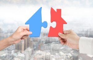 due mani che assemblano puzzle a forma di casa