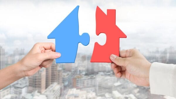 due mani che assemblano puzzle a forma di casa