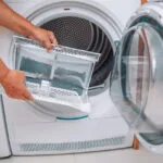 mani che estraggono il filtro dell'asciugatrice