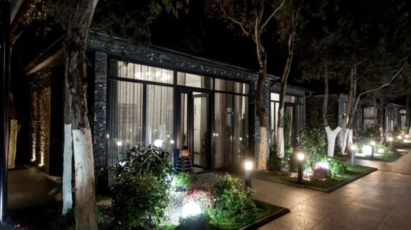 Vialetto illuminato di notte con luci LED da giardino davanti a edifici moderni con ampie vetrate e piante decorative