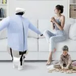 donna seduta sul divano con bambino che gioca e manichino stira-camicie