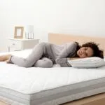 Felice giovane donna afroamericana sul letto con comodo materasso