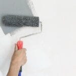 Rullo di vernice. Pittura con vernice grigia su una parete bianca