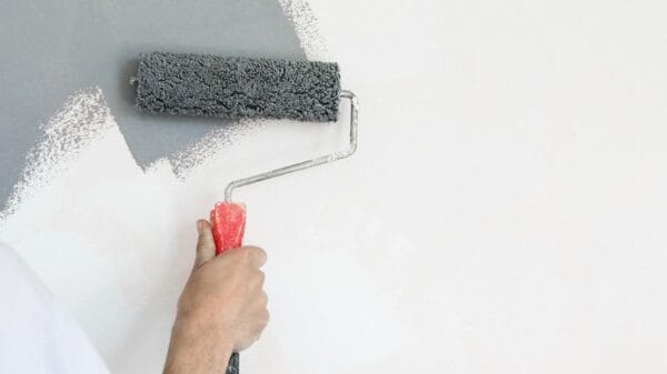 Rullo di vernice. Pittura con vernice grigia su una parete bianca
