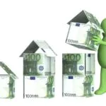 omino che costruisce case con banconote da 100 euro