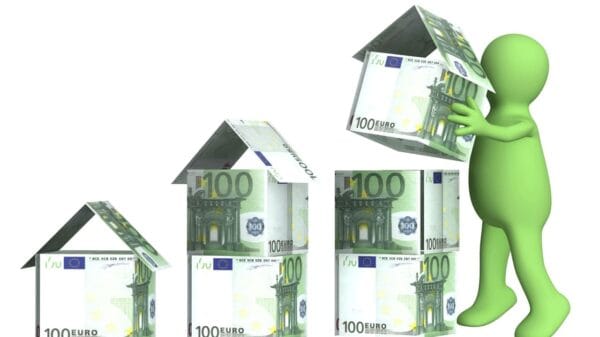 omino che costruisce case con banconote da 100 euro